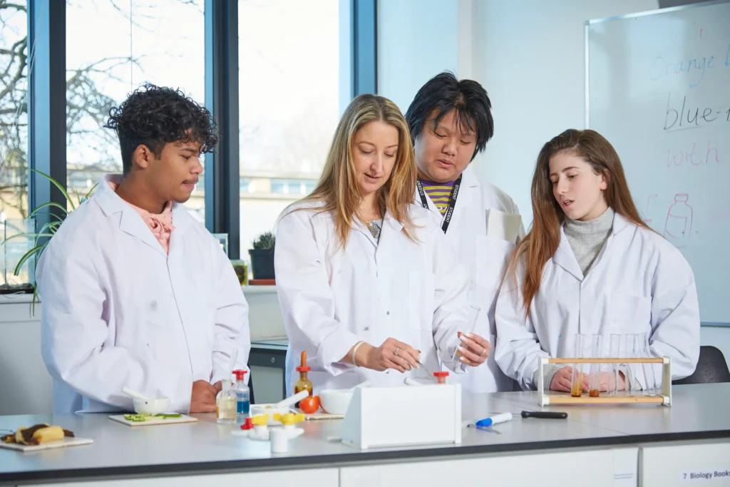 Tutor and students in a science classroom with rack of test tubes.