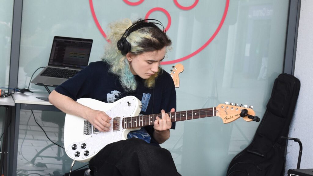 Music student playing guitar at open event