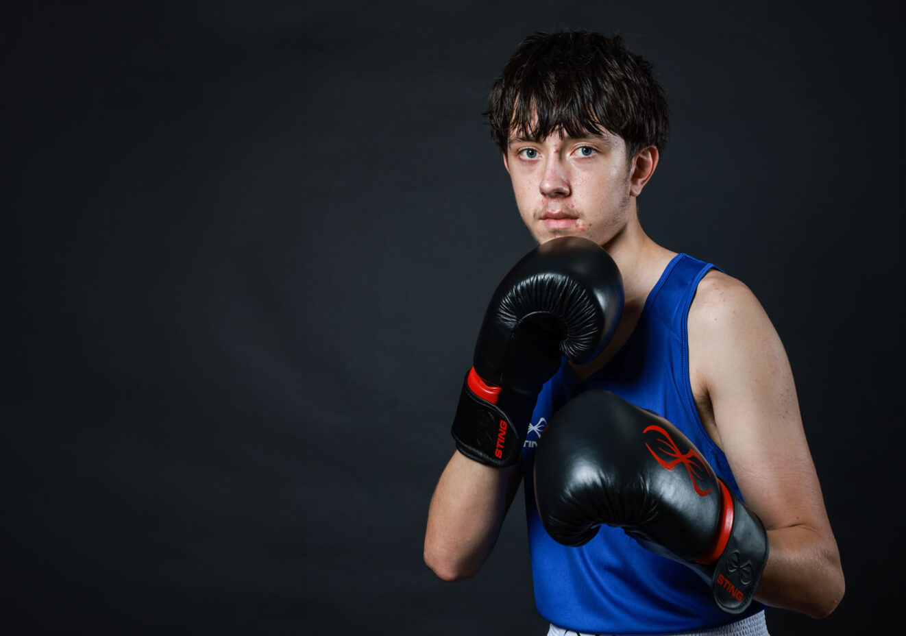 Male boxer wearing boxing gloves in defensive stance.