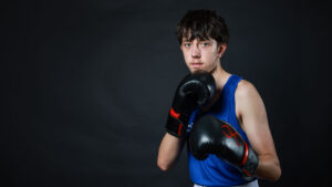 Male boxer wearing boxing gloves in defensive stance.