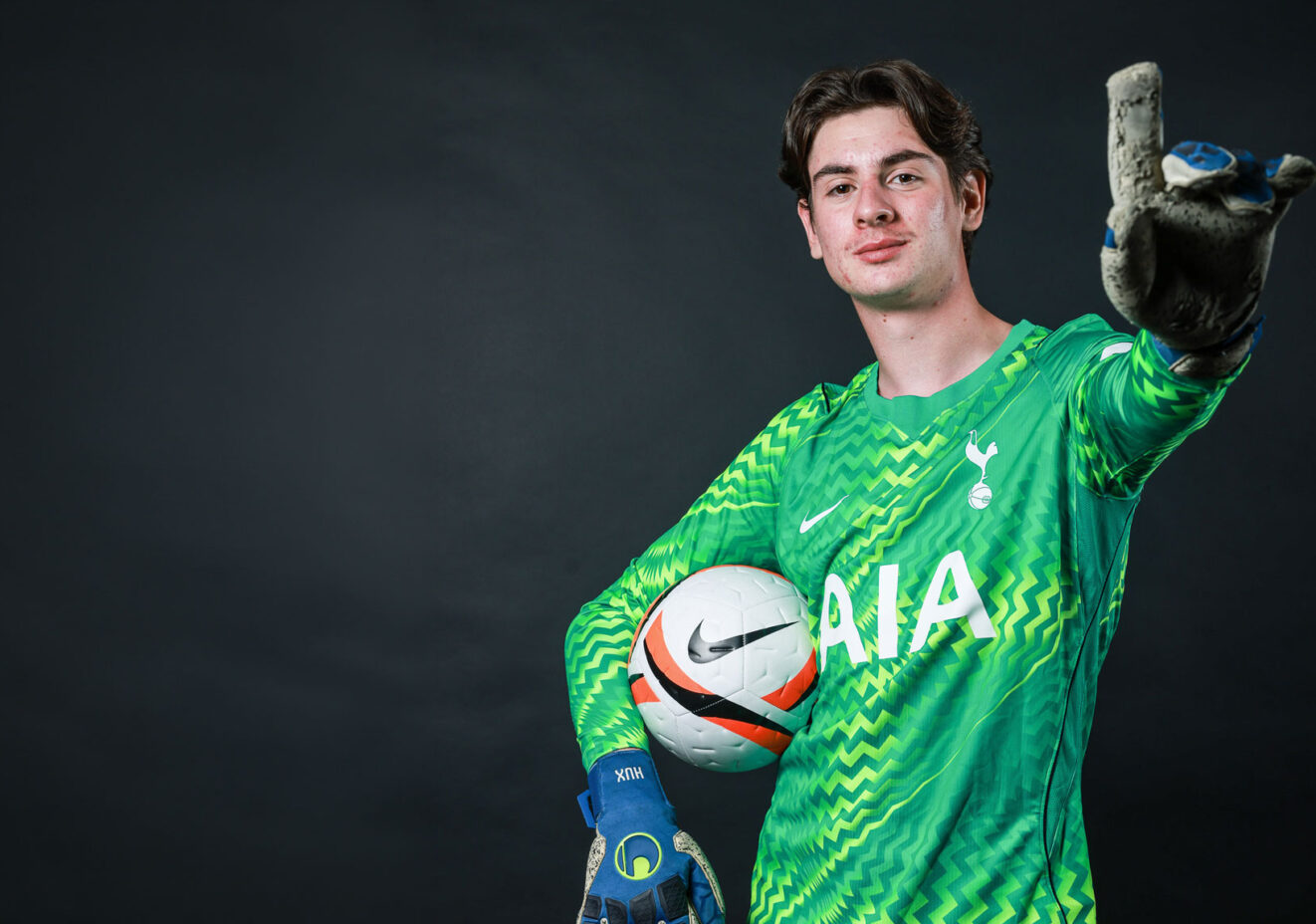 Men's football team goalkeeper holding football and pointing.